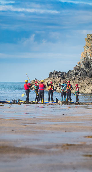 A group of paddle boarders preparing to headout at Porth Dafarch Beach