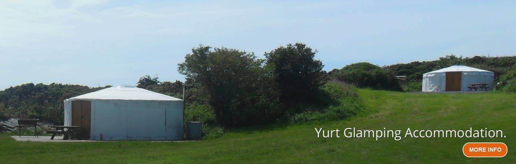 Two white traditional glamping yurts on a grass verge
